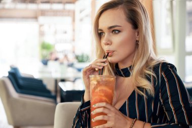 Genç kadın modern bir kafede otururken iyi vakit geçiriyor