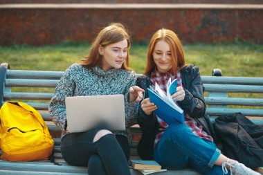 İki öğrenci bir kitap açılış bankta oturmak