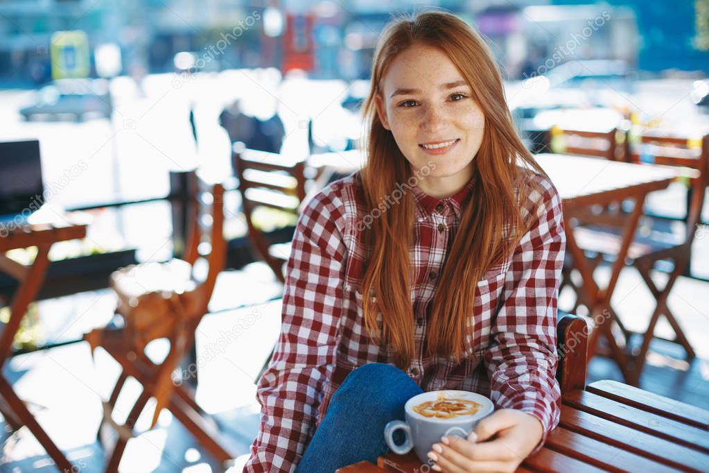 Smiling girl holding a big cup of coffee  while looking to camer