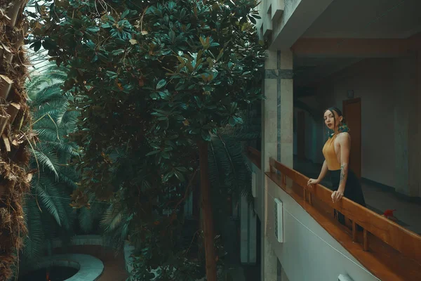 Otel balkonda duran, egzotik ağaçlarıyla çevrili bir tatil zevk dışarı arayan çok şehvetli genç kadın. Dinlenme ve rahatlama kavramı.