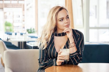 Eşi beklerken modern bir kafede bir masada oturup içki içiyorum, Genç, başarılı bir kadın. Sunuyordu, güzel yüz ve cilt ile şehvetli bluz. Güzel bir cam holding eller.