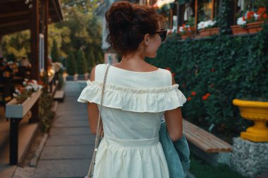 Sokakta, çiçek ve teraslar arka planda yürüyen arkadan görünüm portre genç şehir kadın. Kişi, yaşam biçimi, seyahat ve tatil kavramı