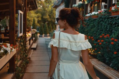 Omuz, çiçek ve arka planda teraslar üzerinde seyir sokak üzerinde yürüme görünümü genç şehir kadın portre geri. Kişi, yaşam biçimi, seyahat ve tatil kavramı