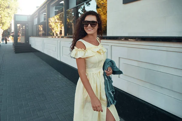 灵感女神的画像在欧洲度过假期 户外照片的微笑 开朗的女孩与棕色卷发 太阳镜 淡黄色的夏季礼服 在城市的早晨走动 — 图库照片
