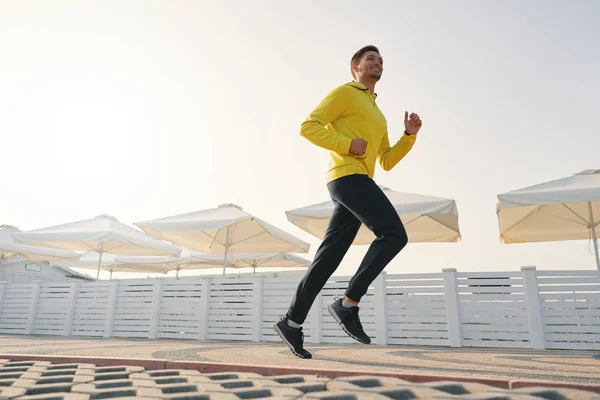 Tam uzunlukta sağlıklı genç adam sabah sahil alanının üzerinde çalışan bir kadeh. Erkek atlet açık havada Sprint. Açı