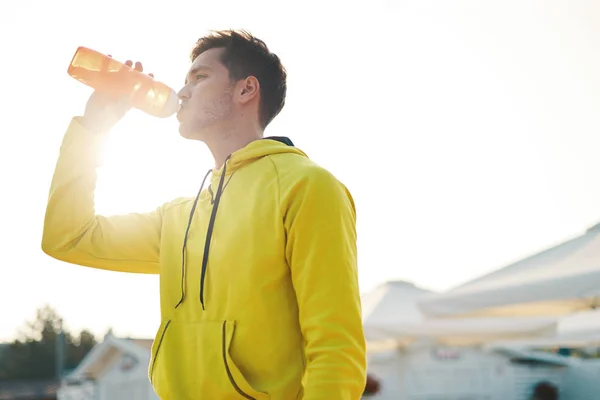 体育概念 男子在沙滩上跑步后喝水 口渴健康运动男性的画像饮用提神饮料 跑步后休息或室外训练 — 图库照片