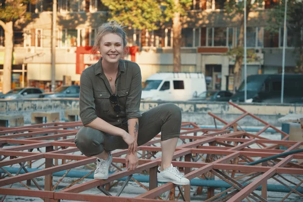 Portrait of a happy young woman posing on metallic construction outdoors. Urban youth occupations. Active people concept.