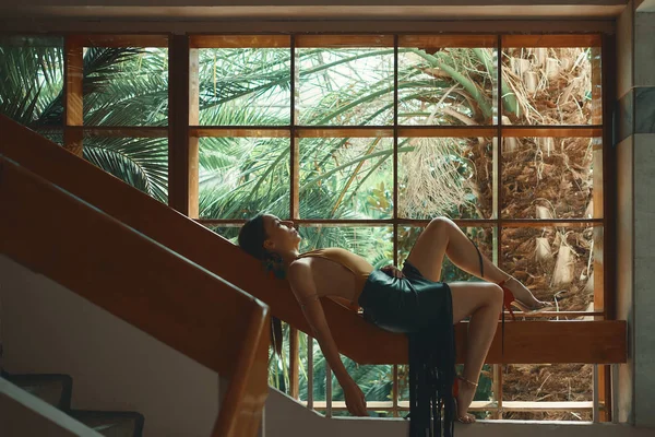 Egzotyczny Relaks Kobieta Leżąc Poręczy Schodów Drewnianych Pobliżu Okna Palmami — Zdjęcie stockowe