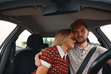 Genç çekici adam kadını araba sürüş sırasında sevgi ile sarılma