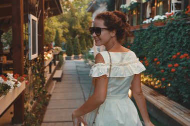 Omuz, çiçek ve arka planda teraslar üzerinde seyir sokak üzerinde yürüme görünümü genç şehir kadın portre geri. Kişi, yaşam biçimi, seyahat ve tatil kavramı