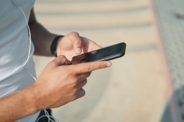 Akıllı telefon kullanan genç adam el atış kırpılmış. Spor ve sağlık denetim kavramı.