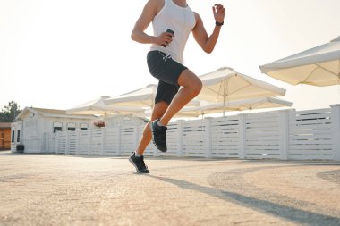 Kentsel runner's bacaklar açısı shot aşağı sokak, güneşli gün arka planda çalıştırmak kapatın. Sağlıklı sabahları kavramı.