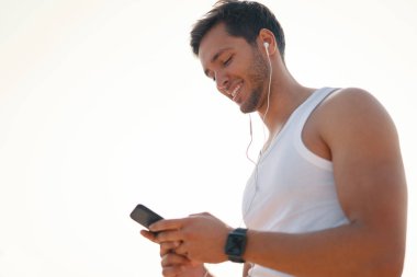 Yakışıklı, mutlu, gülümseyen genç adam akıllı telefon istimal yürüyüş, koşu süre açık havada güneşli, güzel bir günde bir online görüntülü sohbet sahip. Selfie yapma. Yan görünümü. Beyaz arka plan.