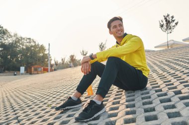 Spor. Fit vücut üzerinde gri Grunge açık havada koşu çalıştırdıktan sonra dinlenme sarı spor giyim gülümseyen adam. Yakışıklı sağlıklı erkek Runner Fitness Egzersiz ve egzersiz sonra mola.