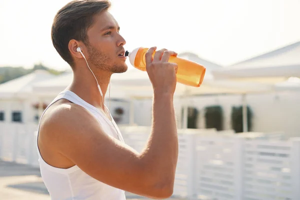 体育概念 男子在沙滩上跑步后喝水 口渴健康运动男性的画像饮用提神饮料 跑步后休息或室外训练 — 图库照片