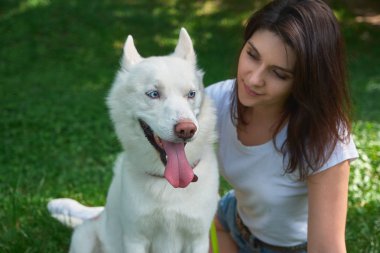 Gülümseyen kadın ve oynak köpek çimenlerin üzerinde açık havada otururken poz dilini çıkarmış, portre