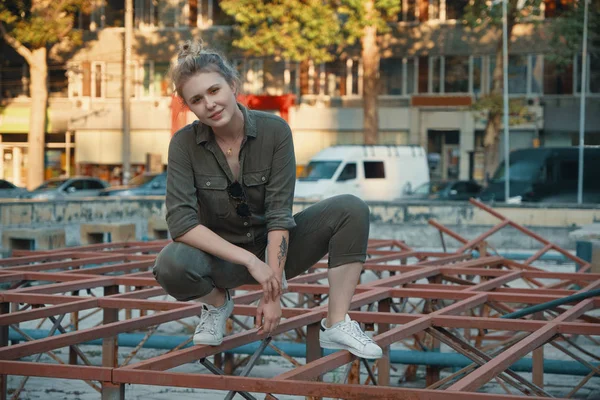 Portrait of a happy young woman posing on metallic construction outdoors. Urban youth occupations. Active people concept.