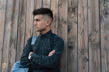 Genç şık öğrenci kopya alanı ile ahşap arka plan üzerinde bir jean sırt çantası ile poz.