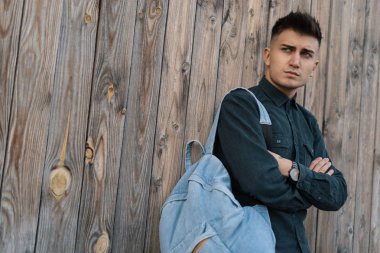 Genç şık öğrenci kopya alanı ile ahşap arka plan üzerinde bir jean sırt çantası ile poz.