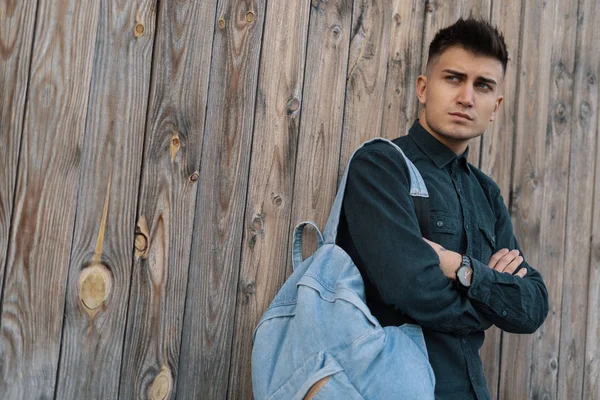 Genç şık öğrenci kopya alanı ile ahşap arka plan üzerinde bir jean sırt çantası ile poz.