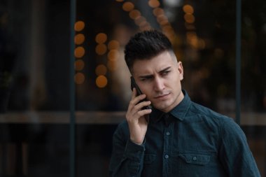 Telefonda konuşan genç adam. İnsanların yüzleri ve modern teknoloji kavramı.