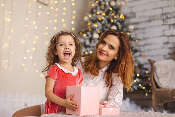 Mutlu anne ve Noel hediye kutusu ile neşeli yürümeye başlayan çocuk kız — Stok fotoğraf