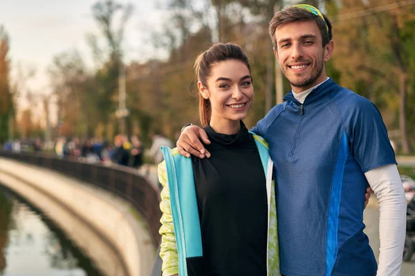 愉快的运动的夫妇画像 男人和女人在拥抱的时候互相微笑 跑步者在跑步后在外面休息 — 图库照片