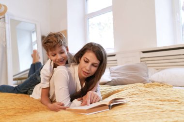 Anne ve oğlu evde yatakta yatıyordu süre bir kitap okuma