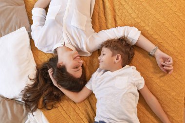 Sahne, anne ve oğul yatakta gülümseyen ve sarılma istirahat rahat ve sıcak. Çocukluk anıları kavramı.