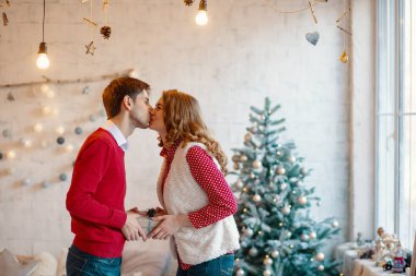 Genç çift birlikte mevcut bir kutusuyla Noel süsleri arka planda tutarak öpüşme