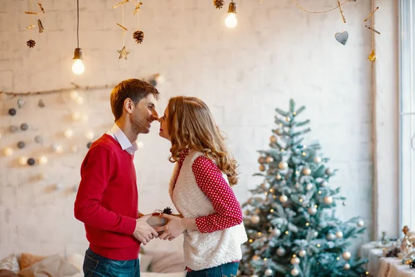 Genç çift birlikte mevcut bir kutusuyla Noel süsleri arka planda tutarak öpüşme