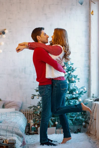 Sarılma ve öpüşme üzerinde Noel ağacı, tam uzunlukta genç çift gösteren resim