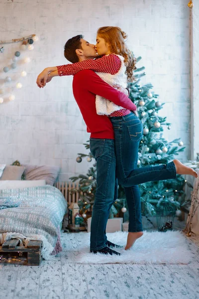 Sarılma ve öpüşme üzerinde Noel ağacı, tam uzunlukta genç çift gösteren resim