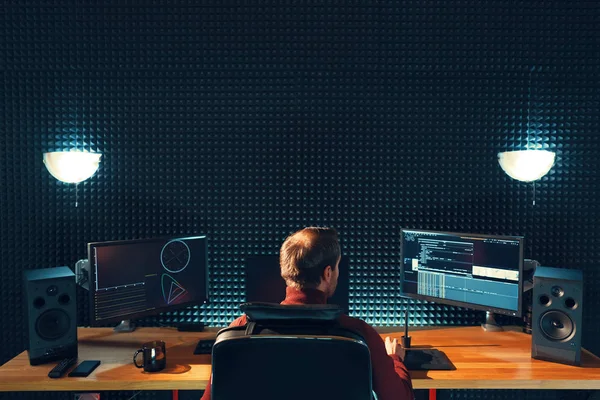 Visão traseira do jovem assistindo gráficos em monitores — Fotografia de Stock