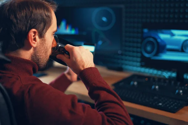 Mladý muž ve studiu pomocí chytrého telefonu a počítače. — Stock fotografie