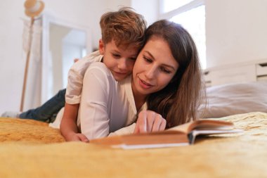 Anne ve oğlu evde yatakta yatıyordu süre bir kitap okuma