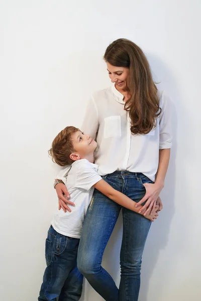 Pretty young mother with son hugging on white background