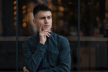 Genç adam düşünceli, bakan portre ışık arka plan ile kapatın. İnsanların yüzleri ve ifadeler kavramı. 