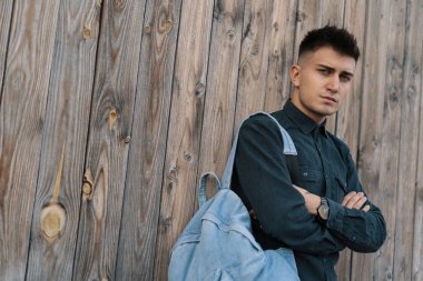 Genç şık öğrenci kopya alanı ile ahşap arka plan üzerinde bir jean sırt çantası ile poz.