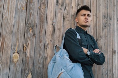 Genç şık öğrenci kopya alanı ile ahşap arka plan üzerinde bir jean sırt çantası ile poz.