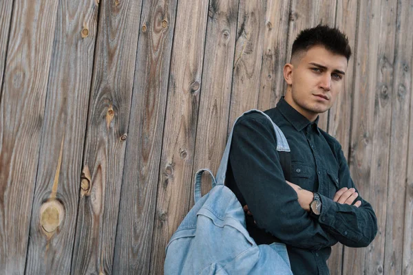 Genç şık öğrenci kopya alanı ile ahşap arka plan üzerinde bir jean sırt çantası ile poz.