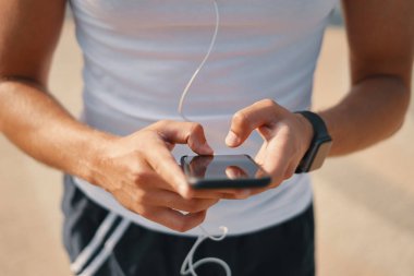 Akıllı telefon kullanan genç adam el atış kırpılmış. Spor ve sağlık denetim kavramı.