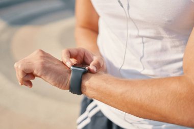 Akıllı izle kullanan kişi. Giyilebilir akıllı saat bilgisayar aygıt üzerinde jestler yapma genç atlet adam eller ve yakın, tanınmayan izlemek. Teknoloji, gadget spor.