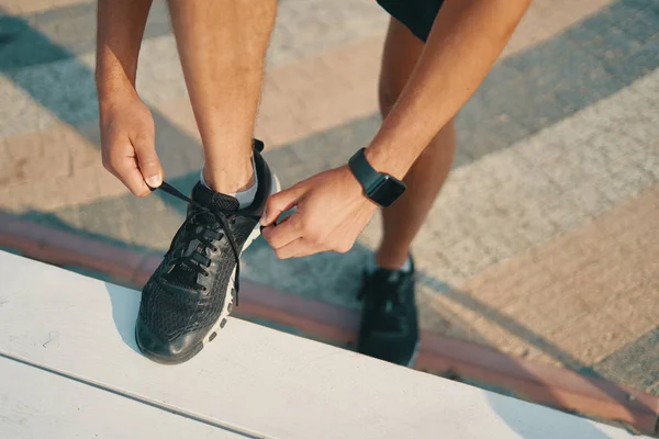运动员把他的黑色运动鞋绑起来 运动男子绑鞋带 而准备运行 左手上的智能手表 特写镜头 — 图库照片