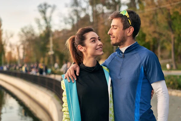 愉快的运动的夫妇画像 男人和女人在拥抱的时候互相微笑 跑步者在跑步后在外面休息 — 图库照片