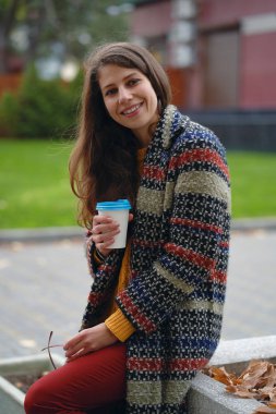 Açık havada kahve içme ceket şık, Genç bir kadın. Modern kentsel kıyafet ve bir mola sırasında şehir sokakta oturmuş gözlük Casual kız.