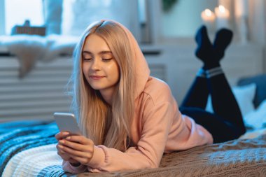Arkadaşlarıyla sohbet ederken, evde yatakta yatan bir akıllı telefon kullanarak pembe Pretty sarışın kız
