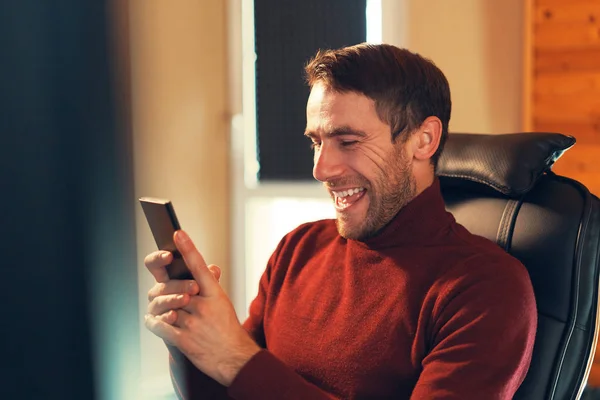 Мужчина счастлив получать хорошие новости, глядя на экран смартфона — стоковое фото