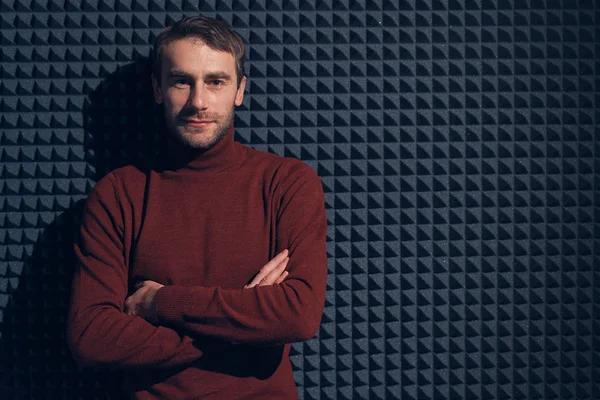 Young, handsome man leaning against grey wall with arms crossed — Stock Photo, Image