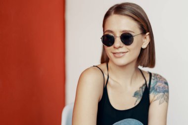 Kırmızı duvarın yanındaki beyaz sandalyede oturan genç kız